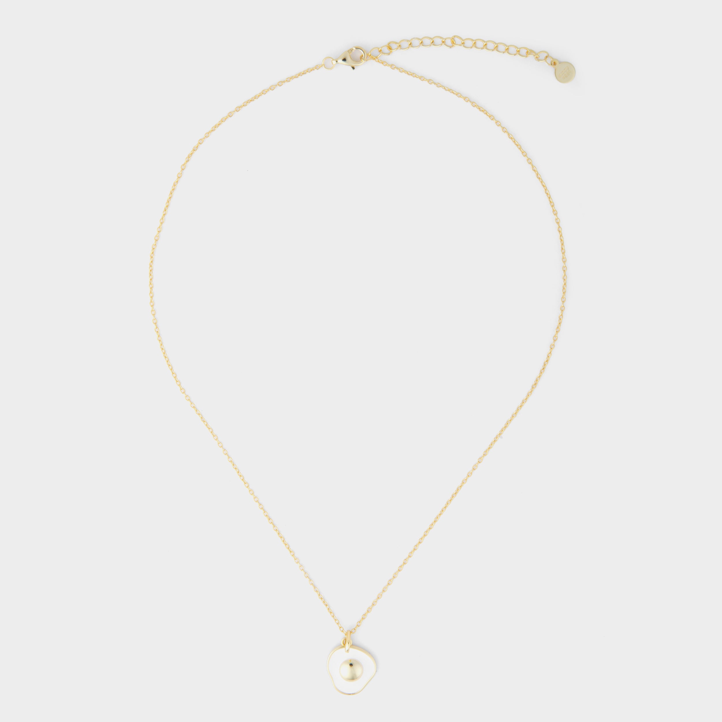 Full view of a sunny-side up egg necklace featuring a glossy gold yolk and white egg white pendant on a gold chain, laid out on a clean white background.