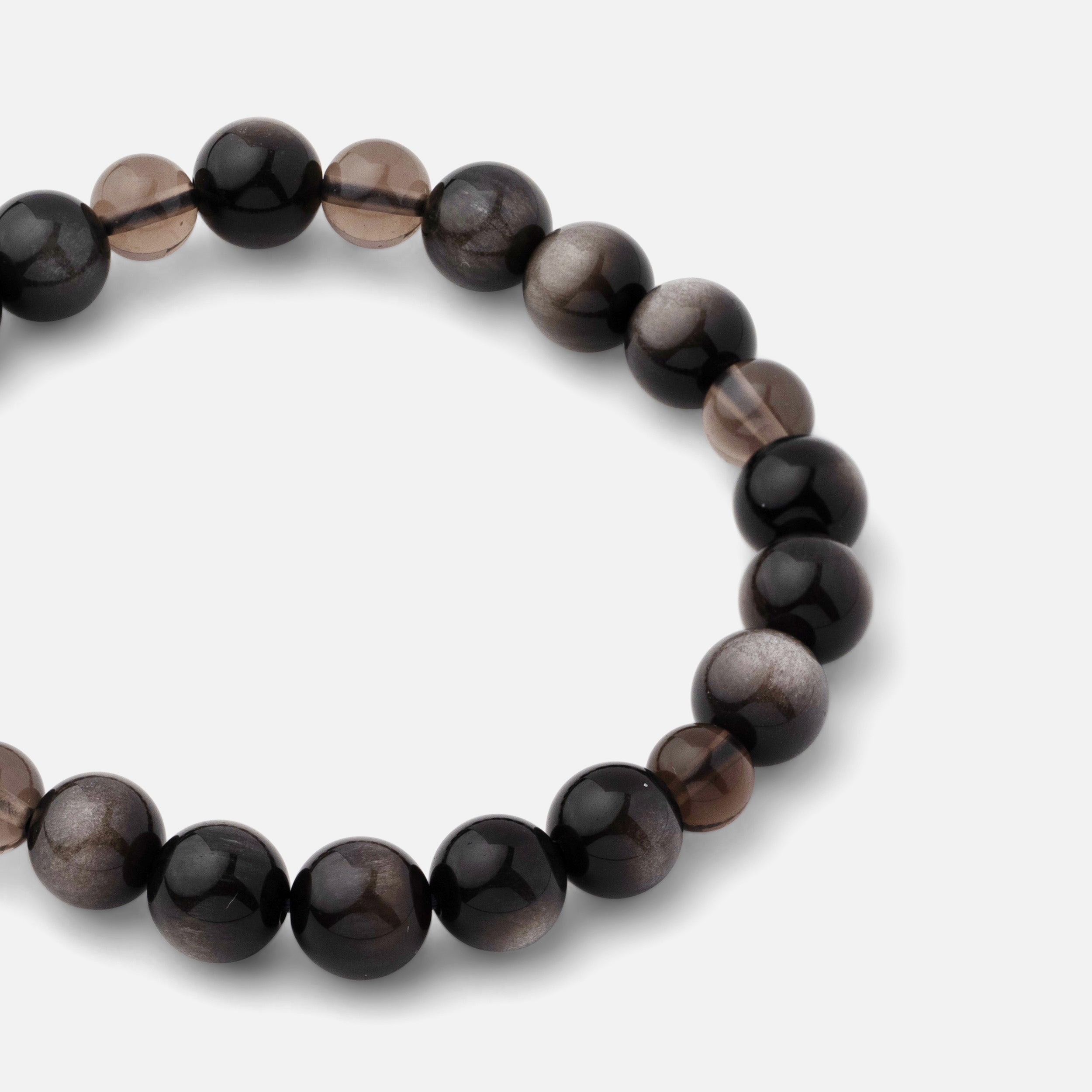 Close-up of a bracelet featuring natural black silver sheen obsidian gemstone beads paired with clear dark brown smoky quartz, showcasing its bold and resilient qualities. Can be worn alone or layered with other silver pieces.