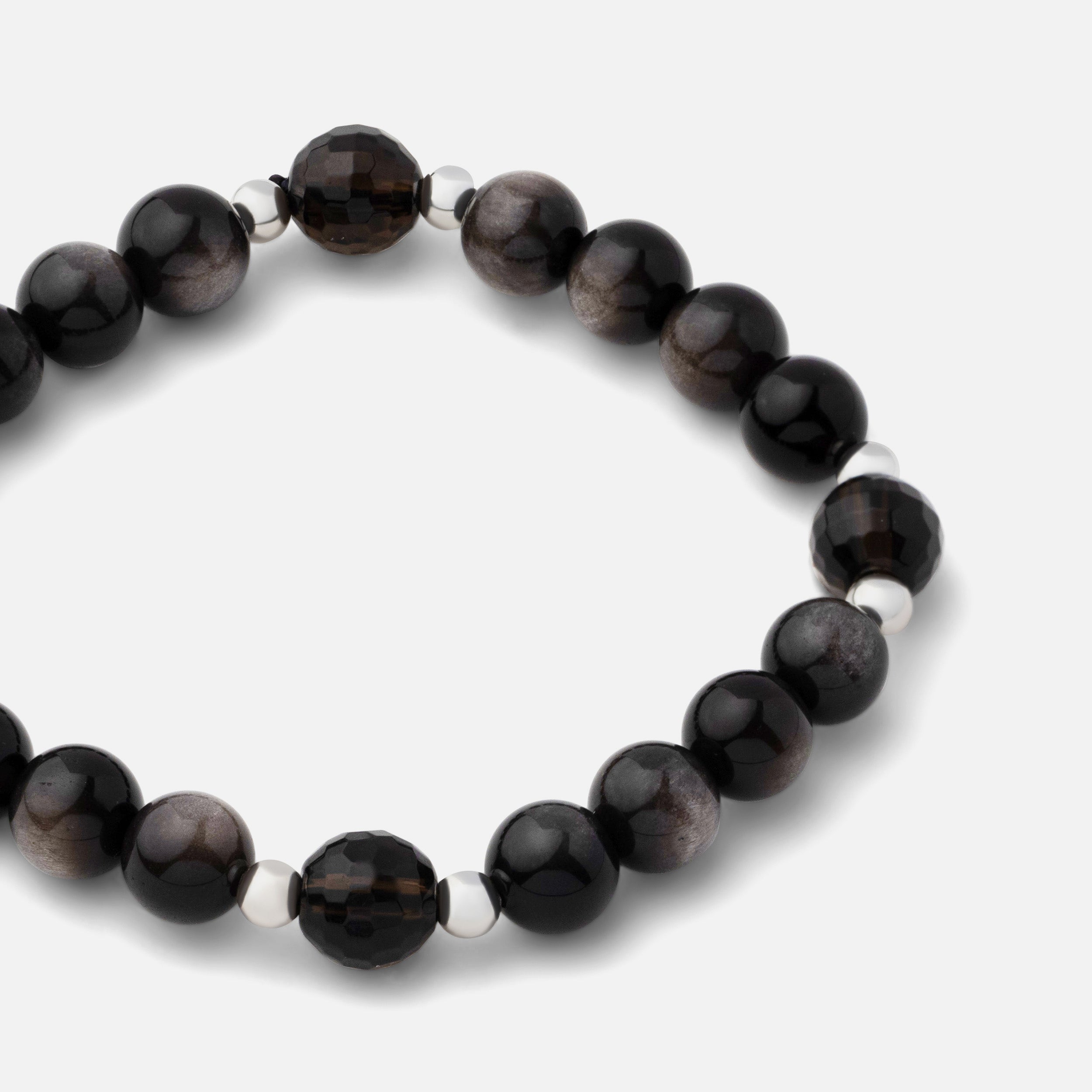 Close-up of a bracelet featuring natural black silver sheen obsidian gemstone beads coupled with clear dark brown smoky quartz, creating a bold and resilient statement. Can be worn alone or layered with other silver pieces.