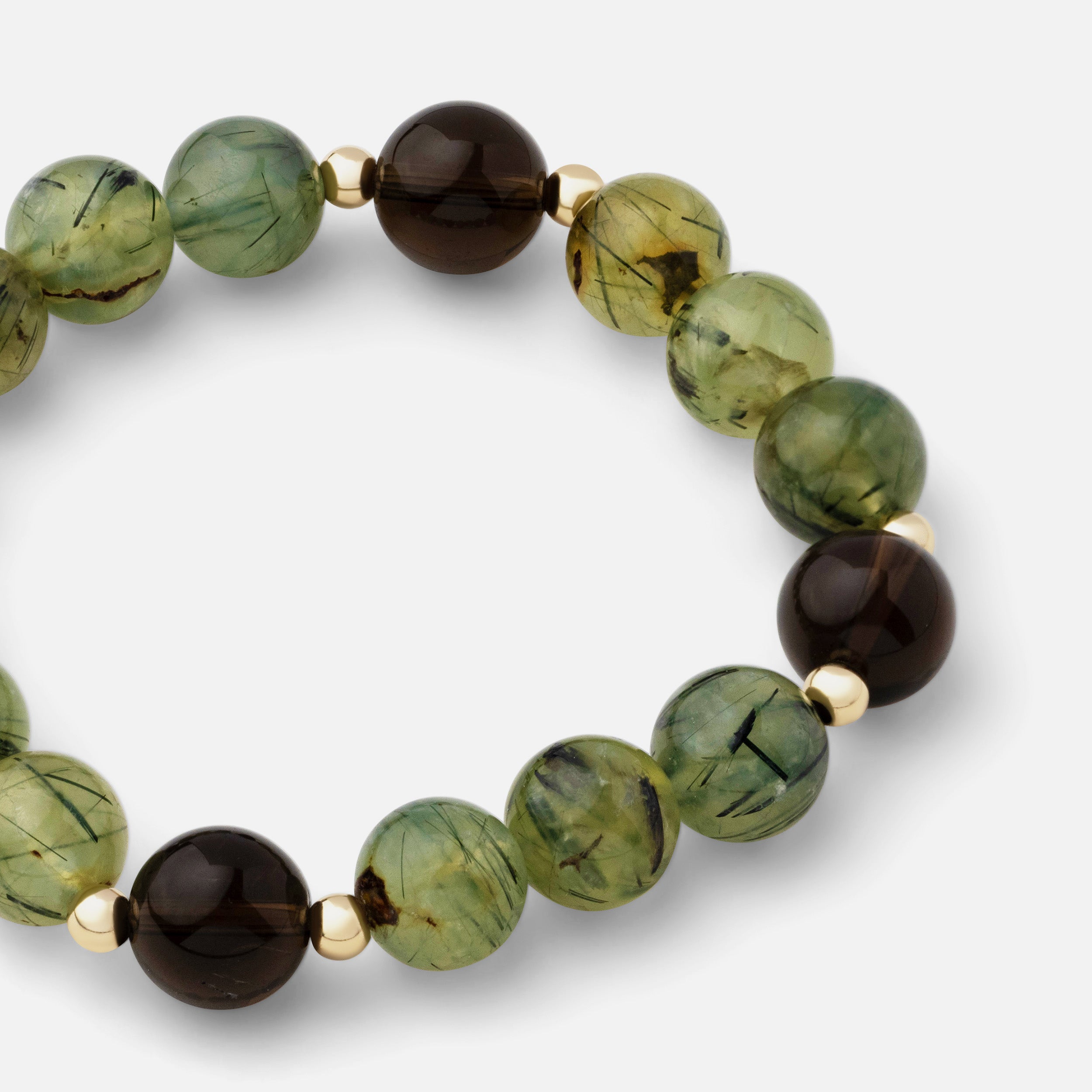 Close-up of a bracelet featuring translucent greenish and yellow prehnite with black needle rutiles, paired with natural smoky quartz gemstones. This elegant piece makes a bold and effortless statement, perfect for mixing and matching with your collection.