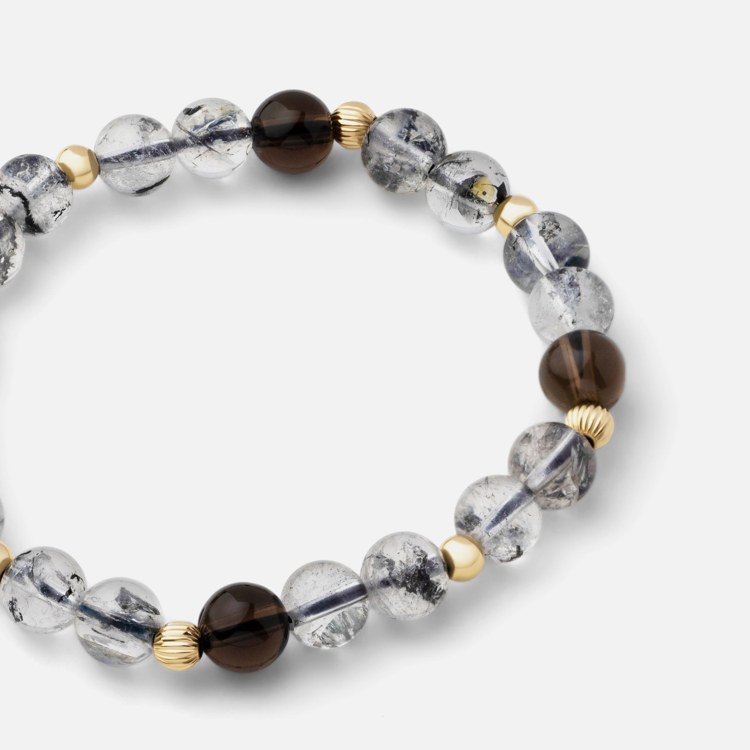 Close-up of a bracelet featuring crystal clear shiny bursts of black inclusion round Herkimer diamond beads paired with clear dark brown smoky quartz, creating a simple yet sophisticated look that celebrates the infinite perfection of nature.