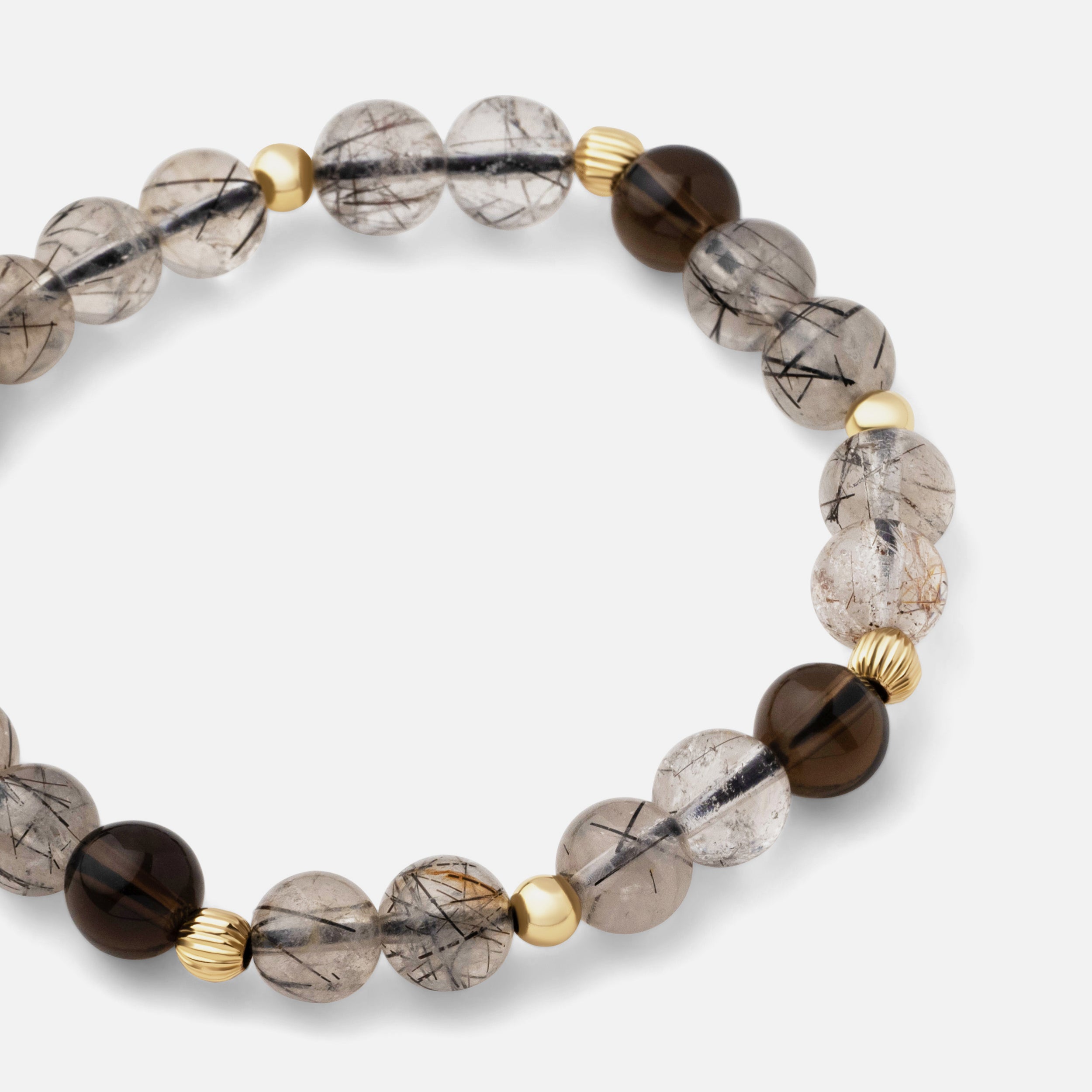 Close-up of a bracelet featuring tiny needles of black rutiles beautifully arrayed in black rutile quartz, paired with clear dark brown smoky quartz for a classic style. Can be worn alone or layered with other gold pieces.