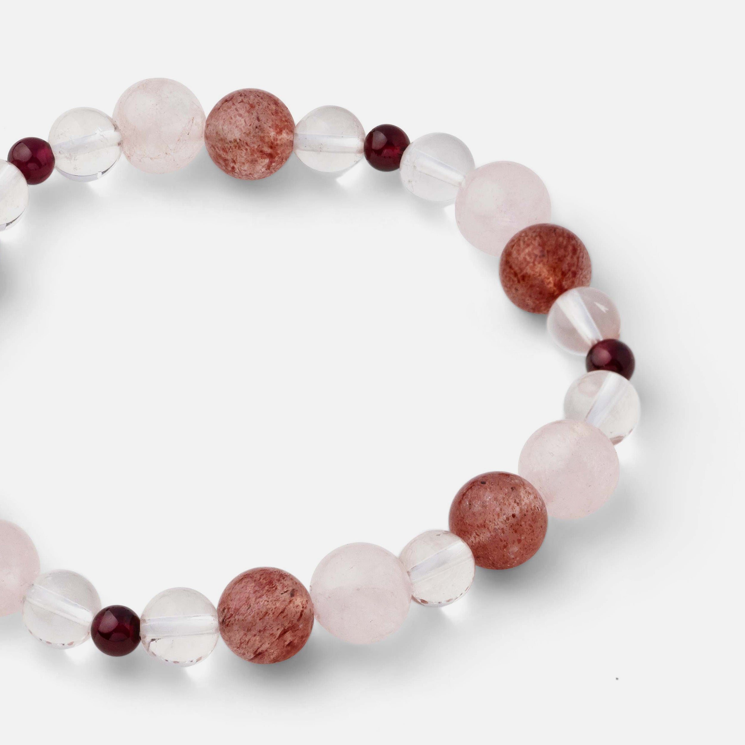 Close-up of a bracelet featuring distinctive red strawberry quartz, blood red garnet, light pink rose quartz, and clear quartz accents, adding a refined touch to your look, ideal for wearing solo or stacked with other bracelets.