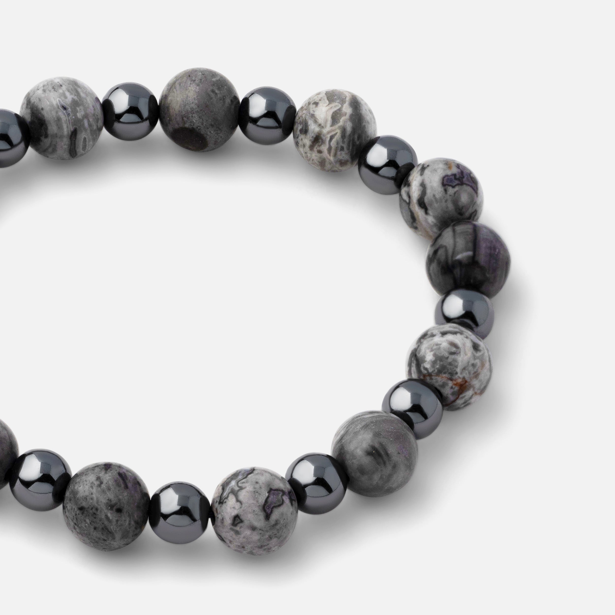 Close-up of a bracelet featuring unique marble streaks of black, gray, and white natural picasso jasper paired with steel gray metallic hematite, showcasing its powerful statement design for casual outfits.