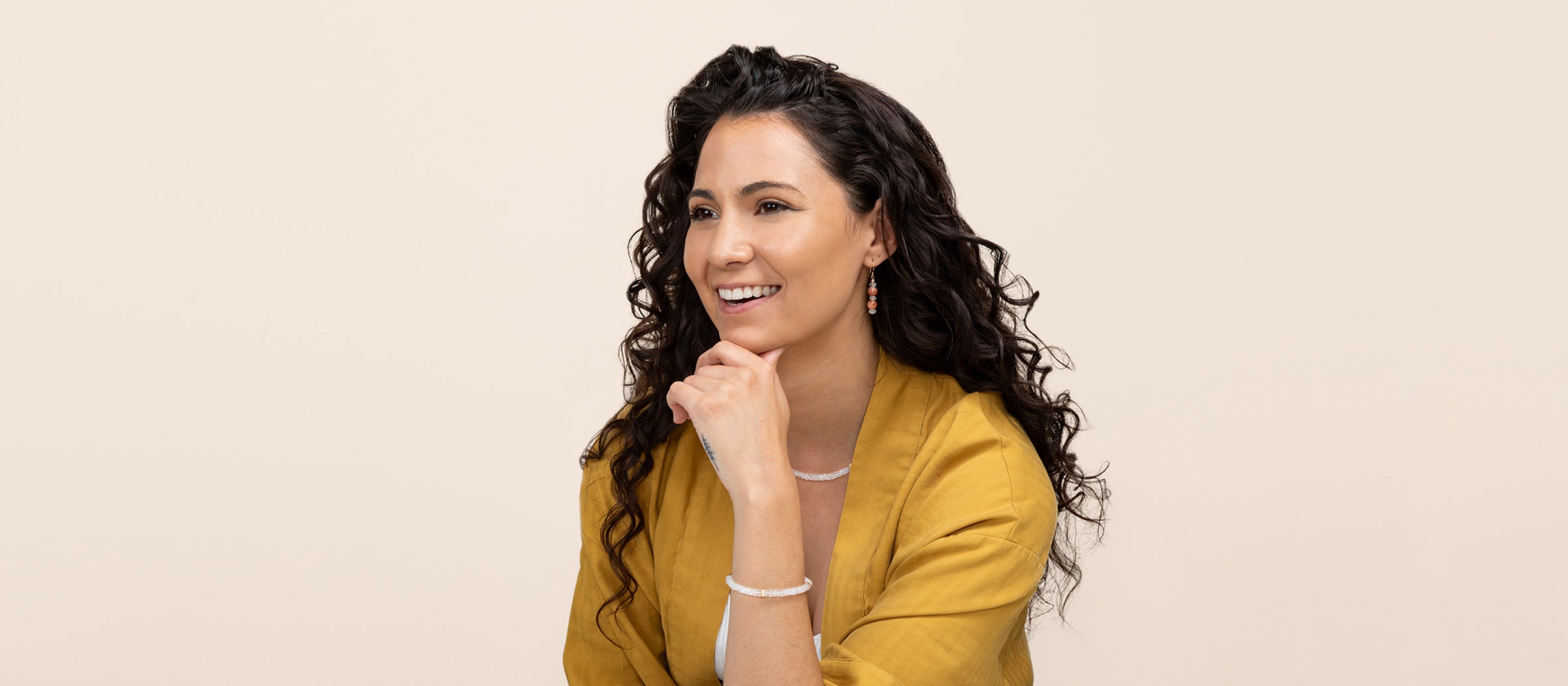 A model smiling and confidently showing off the latest Serenity collection, featuring a Redondo moonstone bracelet, earrings, and necklace with flashy moonstone.