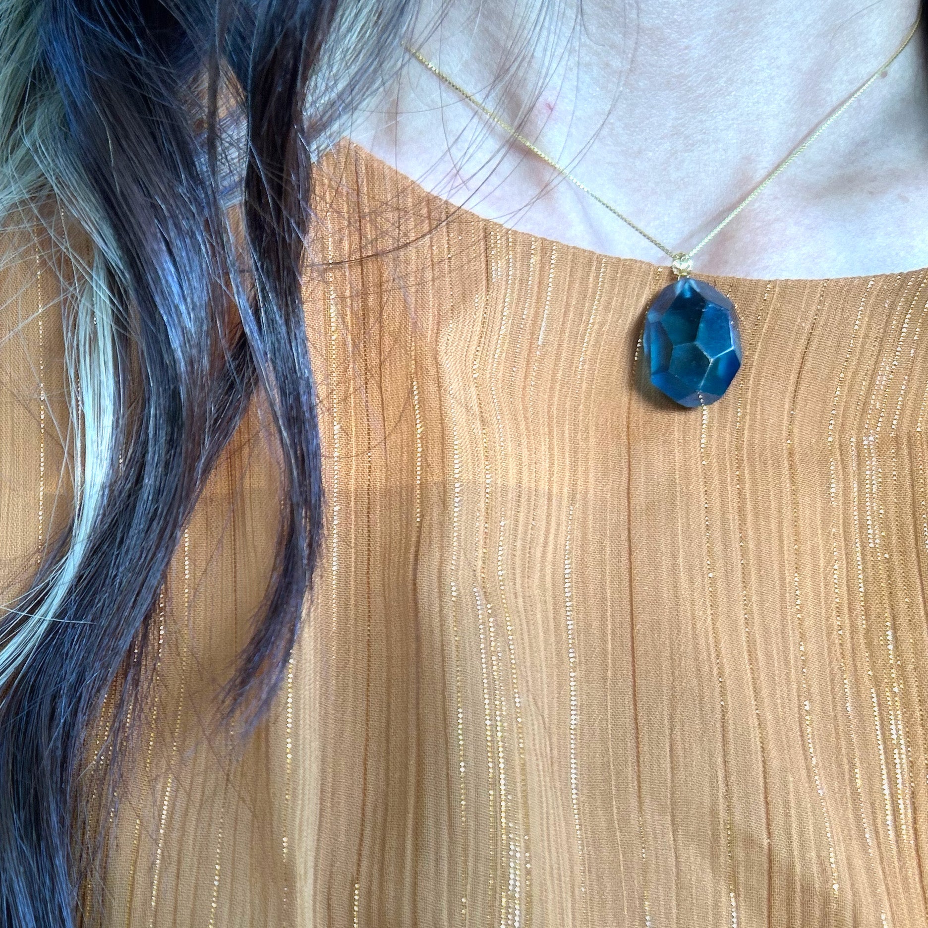 Close-up of a model wearing a deep blue aquamarine pendant with an 18K solid gold clasp, highlighting its glacial beauty and classic style.