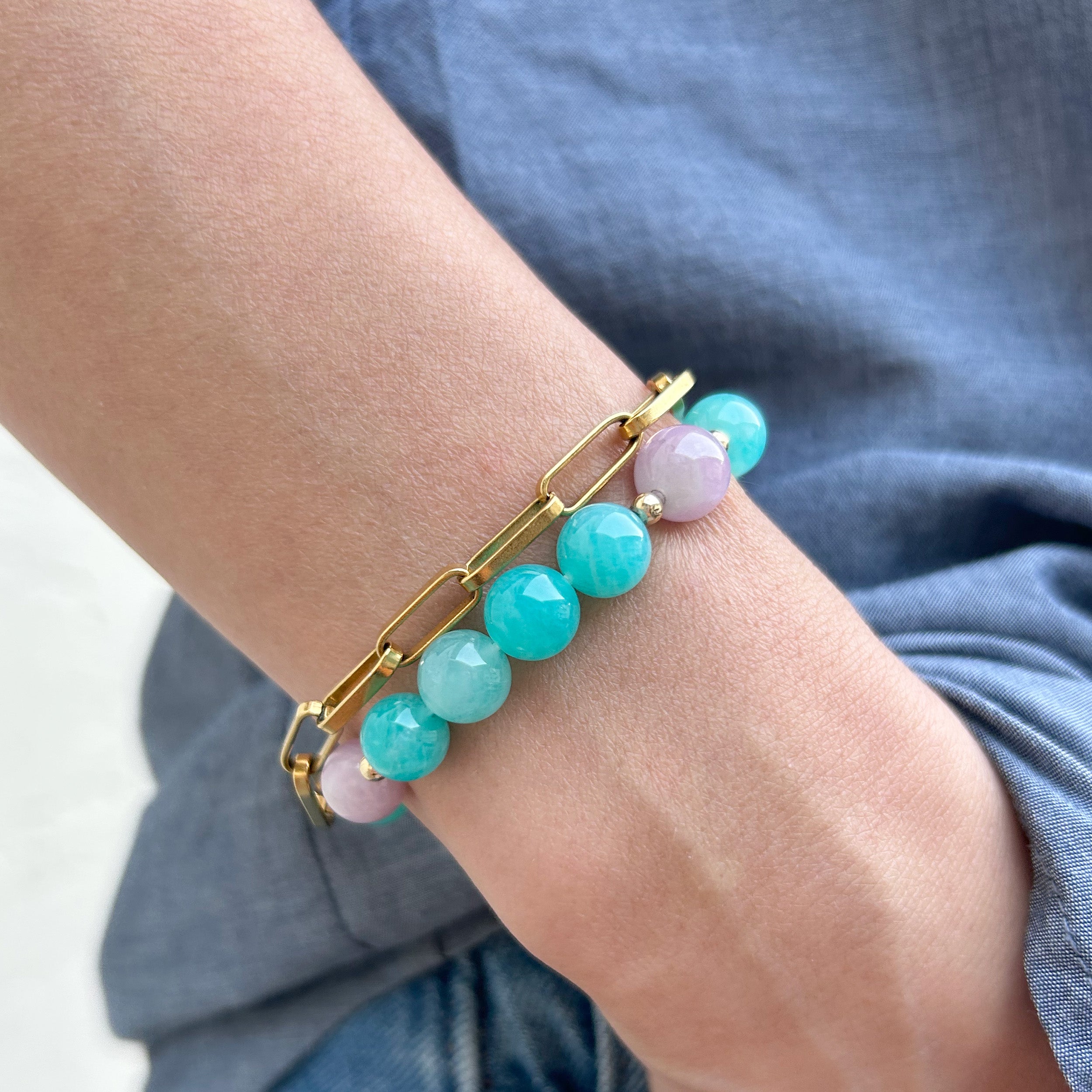 Close-up of a model's wrist wearing a bracelet with ocean blue ice amazonite and pale pink and lavender kunzite, hand in pocket.